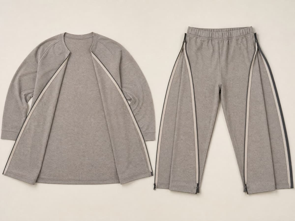 Two matching warm grey garments laid flat side by side, both spread completely open along their side seams into flat open panels.